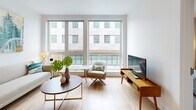 Located at 180 Friendship St in Providence, Rhode Island, this contemporary single-floor residence offers a well-appointed layout designed for modern urban living. The living area is a standout feature, boasting expansive floor-to-ceiling windows that flood the space with natural light and frame views of the surrounding cityscape. Light hardwood flooring runs throughout the common areas, complementing the clean, minimalist aesthetic. The kitchen is thoughtfully designed with sleek gray cabinetry, white countertops, stainless steel appliances, and recessed lighting, accessible directly from the entryway. Multiple bedrooms provide comfortable retreats, each featuring plush carpeting, neutral gray accent walls, generous windows with urban views, and closet storage. The primary bathroom includes a glass-enclosed walk-in shower, white vanity cabinetry, and large-format tile flooring. A second full bathroom offers a white vanity with storage and similarly clean tile finishes. Throughout the residence, a cohesive neutral color palette with contemporary design details creates a calm and inviting atmosphere. The combination of natural light, modern fixtures, and thoughtful spatial planning makes this Providence residence a refined and functional urban home.