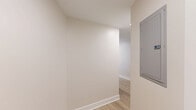 Located at 4500 Connecticut Ave NW in Washington, DC, this thoughtfully designed 2-bedroom, 2-bathroom residence offers a clean, modern aesthetic throughout. Light-toned hardwood flooring flows seamlessly across the single-level layout, creating a cohesive and airy feel. The open kitchen is a standout feature, outfitted with crisp white shaker cabinetry extending to the ceiling, gray quartz countertops, a white subway tile backsplash, stainless steel appliances including a range and over-the-range microwave, and a peninsula that provides additional prep and serving space. The living area is generously proportioned with large windows framing views of the surrounding neighborhood's lush tree canopy and urban streetscape, allowing abundant natural light to fill the room. Both bedrooms are well-sized, featuring neutral walls, hardwood floors, and large windows with city views; the primary bedroom includes a sliding double-panel closet. The two bathrooms are identically styled with hexagonal tile flooring, white subway tile wainscoting, pedestal-style console sinks with matte black fixtures, and frameless glass shower enclosures. A connecting hallway ties the layout together efficiently, completing this polished and move-in-ready Washington, DC residence.