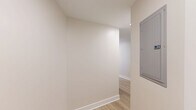 Located at 4500 Connecticut Ave NW in Washington, DC, this thoughtfully designed 2-bedroom, 2-bathroom residence offers a clean, modern aesthetic throughout. Light-toned hardwood flooring flows seamlessly across the single-level layout, creating a cohesive and airy feel. The open kitchen is a standout feature, outfitted with crisp white shaker cabinetry extending to the ceiling, gray quartz countertops, a white subway tile backsplash, stainless steel appliances including a range and over-the-range microwave, and a peninsula that provides additional prep and serving space. The living area is generously proportioned with large windows framing views of the surrounding neighborhood's lush tree canopy and urban streetscape, allowing abundant natural light to fill the room. Both bedrooms are well-sized, featuring neutral walls, hardwood floors, and large windows with city views; the primary bedroom includes a sliding double-panel closet. The two bathrooms are identically styled with hexagonal tile flooring, white subway tile wainscoting, pedestal-style console sinks with matte black fixtures, and frameless glass shower enclosures. A connecting hallway ties the layout together efficiently, completing this polished and move-in-ready Washington, DC residence.