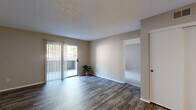 Located at 1045 Morning View Drive in Escondido, California, this single-story residence offers a thoughtfully designed layout encompassing one bedroom, one bathroom, a living room, and a kitchen. The living room is a bright, open space featuring rich wood-style flooring and a sliding glass door fitted with vertical blinds that opens to a private patio, allowing natural light to filter in and providing a seamless indoor-outdoor connection. The neutral, warm-toned walls throughout lend a cohesive and inviting ambiance. The kitchen is efficiently arranged with white cabinetry, gray countertops, and stainless steel appliances including a range and dishwasher, all complemented by wood-style flooring that ties the space together. The bedroom offers plush carpeting, a ceiling fan, a window with outdoor views, and direct access to a closet, creating a comfortable and functional retreat. The bathroom includes a full tub and shower combination with white tile surround, wood-style flooring, and brushed nickel fixtures and grab bar. Textured ceilings are present throughout the home, adding architectural character to this practical and move-in ready residence.