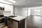 Located in Santa Ana, CA, this single-floor residence offers a clean, modern aesthetic with an efficient and functional layout. The open-concept kitchen is equipped with stainless steel appliances — including a refrigerator, electric range, and over-the-range microwave — complemented by white cabinetry, light quartz countertops, and a double undermount sink set into a peninsula that opens directly to the living area. The living spaces feature light-toned wood-style flooring throughout, neutral wall tones, and textured ceilings that lend a cohesive, airy feel. A sliding glass door leads to a private balcony with outdoor views of the surrounding neighborhood, allowing natural light to fill the main living area. The bedrooms are well-proportioned, each with wood-style flooring, ample wall space, and vertical blind window treatments that provide both light control and privacy. Two full bathrooms mirror each other in design, each featuring a tub-shower combination with sliding glass doors, a single-basin vanity with quartz countertops, dark cabinetry, and large wall-mounted mirrors with overhead lighting. The overall ambiance is bright, clean, and move-in ready, offering a comfortable and practical living environment in the heart of Santa Ana.