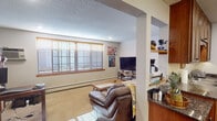 Located at 2360 Commerce Blvd in Mound, Minnesota, this single-floor unit offers a functional and comfortable layout with a cohesive design throughout. The living area is carpeted and well-lit, featuring large windows with wood-trimmed blinds that allow natural light to fill the space. A structural column creates a subtle division between the living area and an adjacent nook with open shelving, providing a convenient pass-through view into the kitchen. The kitchen is efficiently designed with warm medium-toned wood cabinetry, granite-look countertops, hardwood flooring, a double sink, and stainless steel appliances including a refrigerator and range. The bedroom is a comfortable, carpeted room with a window fitted with wood-trimmed blinds, offering a quiet retreat. The full bathroom includes a vanity with dark wood cabinetry, granite-look countertops, a framed mirror, and a shower-tub combo. Textured ceilings are consistent throughout the unit, and baseboard heating is present in the main living areas. The overall layout, as seen in the floorplan view, is compact yet well-organized, making effective use of the available space across all rooms.