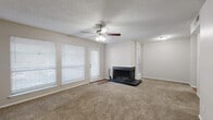 Located at 1200 W Taylor St in Sherman, Texas, this one-bedroom, three-bathroom single-story home offers a well-organized and functional layout across a compact, efficient footprint. The living room serves as the centerpiece of the home, featuring plush wall-to-wall carpeting, a ceiling fan with light kit, a textured ceiling, and multiple windows dressed with white horizontal blinds that allow generous natural light. A wood-burning fireplace with a classic raised hearth adds a warm, inviting focal point to the space, while a private exterior door provides convenient outdoor access. The galley-style kitchen is thoughtfully appointed with gray cabinetry, marble-look laminate countertops, a subway tile backsplash, a stainless steel sink, and wood-look flooring that adds warmth underfoot. The primary bedroom is a comfortable, carpeted retreat with its own ceiling fan, a window for natural light, and access to two closets, including a walk-in closet fitted with dual hanging rods and built-in shelving. The bathrooms feature clean, modern finishes, including a tub-shower combination with large-format gray tile surround. A hallway connects the rooms, completing this practical and well-maintained home.