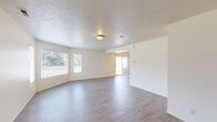 Located at 900 S 1500 E in Clearfield, Utah, this two-story home offers a practical and comfortable layout spread across two evenly sized floors. The main level features an open-concept living room and kitchen area with durable wood-look flooring throughout. The kitchen is well-equipped with light wood cabinetry, generous counter space, a double-basin sink, a skylight panel for added brightness, a kitchen island, and appliances including an electric range, dishwasher, and refrigerator. The living room extends toward a sliding glass door, allowing natural light to fill the space. A staircase with a metal railing connects the two floors from the entry area. Upstairs, three carpeted bedrooms each include ceiling fans and closets, with the generously sized primary bedroom offering ample room for a full furniture arrangement. Two full bathrooms serve the home — one featuring a tub-shower combo with clean white surround, and the other with a wide vanity, wood cabinetry, dark countertops, and a large mirror with stylish lighting. Four closets throughout the home provide plentiful storage. The neutral color palette and consistent finishes create a cohesive, move-in-ready atmosphere throughout.