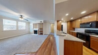 This thoughtfully designed single-floor residence offers two bedrooms and one bathroom across a comfortable and functional layout. The open-concept living and kitchen area serves as the heart of the home, featuring warm hardwood flooring that transitions seamlessly between spaces. The kitchen is well-equipped with rich wood cabinetry, granite countertops, a breakfast bar peninsula, recessed lighting, and black appliances including a range and refrigerator. Crown molding frames the living room, which is highlighted by a cozy fireplace, built-in shelving, and a ceiling fan. Natural light flows in through multiple windows, and a door provides direct outdoor access. The primary bedroom is generously sized with plush carpet, crown molding, a ceiling fan, and a mirrored sliding-door closet. The second bedroom also features soft carpet, a ceiling fan, crown molding, and multiple windows that invite natural light. The shared full bathroom offers a granite-topped vanity with wood cabinetry, a tub-shower combination with sliding glass doors, and hardwood flooring. A dedicated laundry room houses a full-size washer and dryer. Throughout the residence, consistent neutral tones, crown molding, and quality finishes create a cohesive and inviting atmosphere.