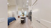 Located at 462 Cherry Street in Macon, GA, this single-floor unit offers a well-appointed open-concept layout that seamlessly integrates the kitchen, living, and sleeping areas into one cohesive space. Soaring ceilings amplify the sense of openness, while large windows invite generous natural light and offer views of the surrounding brick exterior.

The kitchen is a standout feature, showcasing gray shaker-style cabinetry, granite countertops, and a full suite of stainless steel appliances including a French door refrigerator and electric range. A curved kitchen island with pendant lighting and seating provides both a functional workspace and a casual dining option.

The living area is bright and airy, with light wood-style flooring running throughout the unit. The space comfortably accommodates a seating arrangement and offers room for additional furnishings, making it versatile for everyday living.

The bathroom is clean and well-finished, featuring tile surround walls, a tub-shower combination with a decorative curtain, and wood-look flooring that ties into the overall aesthetic of the unit.

Overall, the space presents a modern, neutral palette with high ceilings and efficient use of its footprint, making it a practical and stylish residence in downtown Macon.