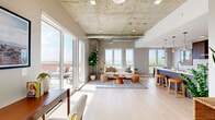 Located in Denver's vibrant West Colfax neighborhood, this two-story residence blends industrial design with modern comfort. The main level opens into a bright, expansive living and kitchen area defined by striking exposed concrete ceilings with visible ductwork, light hardwood floors, and floor-to-ceiling sliding glass doors that flood the space with natural light and lead to a private outdoor terrace with sweeping city views. The open kitchen is equipped with premium stainless steel Bosch appliances, including a gas range, double wall oven, and French door refrigerator, complemented by dark wood cabinetry, a stainless range hood, and a quartz waterfall island with bar seating. A glass-railed staircase connects the two floors with an airy, contemporary feel. The upper level houses both bedrooms, each featuring exposed concrete ceilings, closets, and large windows with scenic Denver views. The primary bedroom includes an en-suite bathroom outfitted with sleek white floating cabinetry, a quartz countertop, and modern fixtures. A second full bathroom and a dedicated laundry area complete the upper floor. Throughout, clean lines, neutral tones, and abundant natural light create a sophisticated urban atmosphere.