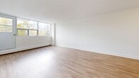 Located at 59 Concession St in Cambridge, Ontario, this 2-bedroom, 1-bathroom unit offers a clean, modern aesthetic throughout. Light oak-toned laminate flooring runs continuously across every room, complementing the crisp white walls and bright, airy atmosphere.

The entrance opens into a central hallway that connects the key living spaces. The galley-style kitchen features white shaker cabinetry, stainless steel appliances including a full-size refrigerator and dishwasher, a subway tile backsplash, and a stainless steel sink — delivering a sleek, functional workspace. The adjacent dining area flows naturally into the living room, which is generously proportioned and bathed in natural light from large floor-to-ceiling windows overlooking lush greenery.

Both bedrooms are well-sized, with the primary bedroom offering ample space and a large sliding-door closet for storage. The second bedroom also benefits from wide windows and abundant natural light. In total, the unit includes four closets, providing excellent storage throughout.

The bathroom is finished with classic white subway tile surrounding a full soaker bathtub, delivering a clean, timeless look. A private balcony with outdoor access adds an additional dimension to the living experience. Baseboard heating is present throughout the unit.