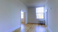 Located at 4920-4950 City Avenue in Philadelphia, Pennsylvania, this single-floor space offers a clean, classic aesthetic with timeless architectural details. The interior showcases warm hardwood flooring throughout, lending a sense of continuity and character across the rooms. Tall ceilings amplify the feeling of openness, while large, multi-pane windows invite an abundance of natural light, creating a bright and welcoming atmosphere. The neutral wall tones provide a versatile backdrop that complements the natural warmth of the wood floors. A classic cast-iron radiator is present, reflecting the building's traditional heating infrastructure and adding to its historic charm. An open doorway connects the main space to an adjoining room, offering a natural flow between areas and suggesting a functional, multi-room layout. The overall ambiance is understated and clean, with a timeless quality rooted in its classic construction details — from the crisp white trim and baseboards to the well-maintained flooring. This space is well-suited for those who appreciate traditional architectural character combined with the convenience of a City Avenue address in Philadelphia.