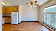 Located at 210 Daniel Dr in Webster, NY, this single-floor unit offers a straightforward and functional layout designed for comfortable everyday living. The kitchen features warm wood-toned cabinetry providing ample storage, hardwood-style flooring, and white appliances including an electric range, refrigerator, and a sink with under-cabinet storage. A textured ceiling and flush-mount light fixture complete the practical space.

The living area transitions from the kitchen and is finished with hardwood-style flooring, a ceiling fan with integrated lighting, and a baseboard heating system that runs along the perimeter. A window along one wall allows natural light to enter, while a wall-mounted air conditioning unit provides climate control during warmer months.

The bedroom is carpeted for added comfort and features its own ceiling fan, baseboard heating, and a window overlooking greenery, bringing in pleasant natural light and outdoor views. A closet is accessible from within the room. Throughout the unit, textured ceilings and neutral wall tones create a clean, understated aesthetic. The 3D floorplan view highlights the efficient use of space across the open-concept living and kitchen zone connecting to the private bedroom area.