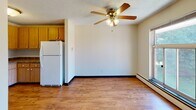 Located at 210 Daniel Dr in Webster, NY, this single-floor unit offers a straightforward and functional layout designed for comfortable everyday living. The kitchen features warm wood-toned cabinetry providing ample storage, hardwood-style flooring, and white appliances including an electric range, refrigerator, and a sink with under-cabinet storage. A textured ceiling and flush-mount light fixture complete the practical space.

The living area transitions from the kitchen and is finished with hardwood-style flooring, a ceiling fan with integrated lighting, and a baseboard heating system that runs along the perimeter. A window along one wall allows natural light to enter, while a wall-mounted air conditioning unit provides climate control during warmer months.

The bedroom is carpeted for added comfort and features its own ceiling fan, baseboard heating, and a window overlooking greenery, bringing in pleasant natural light and outdoor views. A closet is accessible from within the room. Throughout the unit, textured ceilings and neutral wall tones create a clean, understated aesthetic. The 3D floorplan view highlights the efficient use of space across the open-concept living and kitchen zone connecting to the private bedroom area.