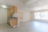 Located at 10500 Sherman Grove Ave in the Sunland-Tujunga neighborhood of Los Angeles, this single-floor residence offers a practical and comfortable layout throughout its main living spaces. The open living and dining area is finished with light-toned laminate wood flooring and features a sliding glass door fitted with vertical blinds, allowing natural light to filter into the space. A textured popcorn ceiling runs throughout the main areas, lending a classic character to the interior.

The galley-style kitchen is efficiently designed with warm honey-toned wood cabinetry lining both sides, complemented by granite-look countertops, a double stainless steel sink, a white electric range with overhead ventilation, and tile flooring underfoot. Ample upper and lower cabinet storage makes this kitchen highly functional.

The bedroom areas feature plush carpeting and are connected to the main living space via open doorways. One area includes a set of full mirrored sliding closet doors with gold-tone frames, adding depth and light to the room. The bathroom is clean and straightforward, equipped with a white tub and shower combination featuring chrome fixtures. Warm neutral tones throughout the walls and trim create a cohesive and welcoming ambiance across the entire unit.