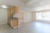 Located at 10500 Sherman Grove Ave in the Sunland-Tujunga neighborhood of Los Angeles, this single-floor residence offers a practical and comfortable layout throughout its main living spaces. The open living and dining area is finished with light-toned laminate wood flooring and features a sliding glass door fitted with vertical blinds, allowing natural light to filter into the space. A textured popcorn ceiling runs throughout the main areas, lending a classic character to the interior.

The galley-style kitchen is efficiently designed with warm honey-toned wood cabinetry lining both sides, complemented by granite-look countertops, a double stainless steel sink, a white electric range with overhead ventilation, and tile flooring underfoot. Ample upper and lower cabinet storage makes this kitchen highly functional.

The bedroom areas feature plush carpeting and are connected to the main living space via open doorways. One area includes a set of full mirrored sliding closet doors with gold-tone frames, adding depth and light to the room. The bathroom is clean and straightforward, equipped with a white tub and shower combination featuring chrome fixtures. Warm neutral tones throughout the walls and trim create a cohesive and welcoming ambiance across the entire unit.