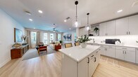 Located at 500 E Rivulon Blvd in Gilbert, AZ, this well-appointed 2-bedroom, 2-bathroom residence offers a cohesive, modern aesthetic across its single-level floor plan. The open-concept kitchen and living area serves as the heart of the home, where light hardwood-style flooring, recessed lighting, and a ceiling fan create a bright, airy atmosphere. The kitchen features white cabinetry with matte black hardware, quartz countertops, a white subway tile backsplash, stainless steel appliances, a deep undermount sink, and a central island with stylish pendant lighting — ideal for both cooking and entertaining. The living area is generously sized with large windows that invite natural light and provide access to a private balcony. The spacious primary bedroom is carpeted and includes a ceiling fan, large windows, and access to a well-sized walk-in closet. The second bedroom offers similar comfort with hardwood-style flooring and natural light. Both bathrooms are finished with white tile, clean vanities, and matte black fixtures. A dedicated in-unit laundry room with a full-size washer and dryer adds everyday convenience. The hallway connects all areas seamlessly, completing a functional and stylish layout.