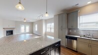Located at 1507 Malachi Ct in High Point, NC, this single-story home offers a well-designed open-concept layout that seamlessly connects the kitchen, dining, and living areas. The kitchen is a standout feature, showcasing granite countertops on both a large center island and perimeter surfaces, gray shaker-style cabinetry with ample storage, a tile backsplash, and a full suite of stainless steel appliances including a range, microwave, dishwasher, and refrigerator. Pendant and track lighting illuminate the space throughout. The living room is bright and welcoming, with warm hardwood-style flooring, a ceiling fan, a tiled fireplace, and French doors that open to the outdoors, allowing natural light to fill the room. Bedrooms are carpeted and feature ceiling fans and windows that bring in natural light. The walk-in closet includes wire shelving for organized storage. Bathrooms are finished with marble-style tile surrounding the tub and shower, granite vanity tops, and dark cabinetry. Tile flooring completes the bathroom spaces. Neutral wall tones and clean finishes throughout the home create a cohesive and move-in-ready aesthetic.