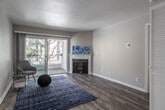 Located at 11475 Central Ave in Chino, California, this single-floor residence offers a well-designed layout with consistent wood-look flooring flowing throughout the entire space. The living room serves as the focal point of the home, centered around a charming corner fireplace with a classic white mantel. Large sliding glass doors bathe the room in natural light and provide direct access to a private outdoor patio, where mature trees create a pleasant, shaded setting.

The galley-style kitchen is thoughtfully updated, featuring white shaker cabinetry, stone-tone countertops, a decorative tile backsplash, and a full suite of stainless steel appliances including a gas range, microwave, and dishwasher. The neutral-toned bedrooms offer ample space and natural light through window blinds, with clean, textured walls and crisp white baseboards throughout. A generously sized walk-in closet with built-in shelving and hanging rods provides excellent storage capacity.

The bathroom is finished with a white vanity, stone-tone countertop, undermount sink, and a large mirror, maintaining the home's clean, modern aesthetic. Overall, the space presents a cohesive, move-in-ready interior with updated finishes and a neutral palette well-suited to a variety of living styles.