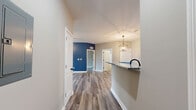This well-appointed single-story home in Richmond, Kentucky offers three bedrooms, two bathrooms, and a dedicated laundry room within a thoughtfully designed floor plan. Throughout the home, durable hardwood-style flooring in a cool gray tone provides a cohesive, modern aesthetic.

The open living room makes a strong first impression with a bold blue accent wall, ceiling fan, and a glass door that opens onto a private balcony overlooking a lush, open green landscape — an ideal spot for relaxing and enjoying the outdoors.

The kitchen is efficiently laid out with white cabinetry, granite-look countertops, a peninsula with a sink, recessed lighting, and black appliances including a refrigerator and range. A hallway connects the kitchen to the laundry area and rear entry.

The primary bedroom is generously sized, featuring the same bold blue accent wall found in the living area, a ceiling fan, and direct access to an en suite bathroom. The en suite includes a granite-topped vanity with white cabinetry and matte black hardware. The secondary bathroom offers a full tub-shower combination with matte black fixtures. The additional bedrooms are bright and neutral, with large windows allowing natural light to fill each room.