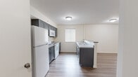 Located at 58 Hampshire Ln in Gibsonia, PA, this single-floor, one-bedroom, one-bathroom residence offers a well-designed layout with a clean, modern aesthetic. Light wood-style flooring runs throughout the entire unit, creating a cohesive and bright atmosphere.

The kitchen is a standout feature, equipped with gray shaker-style cabinetry on both upper and lower levels, light-toned countertops, a double stainless steel sink, and a full suite of white appliances including a refrigerator, electric range, and over-the-range microwave. A peninsula with a darker countertop provides additional workspace and defines the transition into the living area. A window allows natural light to fill the kitchen.

The living room is a comfortably sized, open space featuring a wall-mounted HVAC unit and a window with blinds that brings in natural light. A ceiling fan with a light fixture adds both style and functionality to the room.

The bedroom offers a well-proportioned layout with a window overlooking greenery, a ceiling fan, and a wall HVAC unit. A bifold closet door provides convenient built-in storage, and a secondary door leads to an adjacent area.

The bathroom includes a full tub-shower combo with a white surround, a toilet, and a vanity with a white countertop and gray cabinetry, maintaining the consistent modern palette found throughout the home.