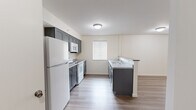 Located at 58 Hampshire Ln in Gibsonia, PA, this single-floor, one-bedroom, one-bathroom residence offers a well-designed layout with a clean, modern aesthetic. Light wood-style flooring runs throughout the entire unit, creating a cohesive and bright atmosphere.

The kitchen is a standout feature, equipped with gray shaker-style cabinetry on both upper and lower levels, light-toned countertops, a double stainless steel sink, and a full suite of white appliances including a refrigerator, electric range, and over-the-range microwave. A peninsula with a darker countertop provides additional workspace and defines the transition into the living area. A window allows natural light to fill the kitchen.

The living room is a comfortably sized, open space featuring a wall-mounted HVAC unit and a window with blinds that brings in natural light. A ceiling fan with a light fixture adds both style and functionality to the room.

The bedroom offers a well-proportioned layout with a window overlooking greenery, a ceiling fan, and a wall HVAC unit. A bifold closet door provides convenient built-in storage, and a secondary door leads to an adjacent area.

The bathroom includes a full tub-shower combo with a white surround, a toilet, and a vanity with a white countertop and gray cabinetry, maintaining the consistent modern palette found throughout the home.