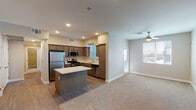 This single-floor residence is designed with a clean, contemporary aesthetic and a practical, open layout. The kitchen serves as a central hub of the living space, outfitted with medium-toned cabinetry, light quartz countertops, and a full suite of stainless steel appliances including a gas range, microwave, dishwasher, and refrigerator. A center island provides additional prep and dining space, while recessed lighting illuminates the area overhead. Wood-look flooring runs throughout the kitchen and transitions seamlessly into the adjacent living area, which features plush carpeting and a ceiling fan. Windows along the exterior wall allow natural light to fill the space and offer views of the surrounding area.

The bedrooms are carpeted and well-proportioned, each featuring a window with blinds and neutral wall tones that create a calm, restful atmosphere. One bedroom includes a ceiling fan for added comfort. The unit includes two bathrooms: one with a tub-shower combination and a wood-toned vanity, and another with a glass-enclosed walk-in shower and a grab bar. Both bathrooms feature wood-look flooring. A dedicated in-unit laundry area with a washer and dryer is accessible directly from the kitchen, adding significant everyday convenience to the overall layout.