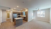 This single-floor residence is designed with a clean, contemporary aesthetic and a practical, open layout. The kitchen serves as a central hub of the living space, outfitted with medium-toned cabinetry, light quartz countertops, and a full suite of stainless steel appliances including a gas range, microwave, dishwasher, and refrigerator. A center island provides additional prep and dining space, while recessed lighting illuminates the area overhead. Wood-look flooring runs throughout the kitchen and transitions seamlessly into the adjacent living area, which features plush carpeting and a ceiling fan. Windows along the exterior wall allow natural light to fill the space and offer views of the surrounding area.

The bedrooms are carpeted and well-proportioned, each featuring a window with blinds and neutral wall tones that create a calm, restful atmosphere. One bedroom includes a ceiling fan for added comfort. The unit includes two bathrooms: one with a tub-shower combination and a wood-toned vanity, and another with a glass-enclosed walk-in shower and a grab bar. Both bathrooms feature wood-look flooring. A dedicated in-unit laundry area with a washer and dryer is accessible directly from the kitchen, adding significant everyday convenience to the overall layout.