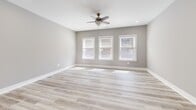 Located at 225 Park Ave in Baltimore, MD, this thoughtfully updated 2-bedroom, 1-bathroom residence offers a clean, modern aesthetic across a single, well-organized floor. Light gray walls, crisp white trim, and wood-look luxury vinyl plank flooring run throughout, creating a cohesive and contemporary feel.

The open kitchen and living area serves as the heart of the home, showcasing white shaker cabinetry extending to the ceiling, quartz countertops with subtle veining, a peninsula with an undermount sink, and stainless steel appliances including a French door refrigerator, electric range, microwave, and dishwasher. Pendant lighting above the peninsula adds a refined touch.

The spacious primary bedroom receives generous natural light through three large windows framed in white trim and is equipped with a ceiling fan and recessed lighting. The second bedroom also features windows, a ceiling fan, and recessed lighting, offering a bright and comfortable retreat.

The full bathroom is finished with large-format gray tile surrounding a soaking tub and shower combination, providing a clean, modern look. Two hallways connect the rooms efficiently, and a visible electrical panel indicates practical utility access. The overall design emphasizes functionality and modern style throughout.