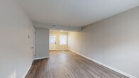 Located at 1040 McQuay St in Charlotte, NC, this two-story home offers a clean, updated interior with a consistent design aesthetic throughout. The main level features an open entry area with a paneled front door and large windows that allow natural light to fill the space. Wood-look flooring in warm tones runs throughout both floors, complementing the neutral gray and beige wall palette and crisp white baseboards.

The kitchen is well-appointed with white shaker-style cabinetry, granite countertops featuring gray and white veining, a stainless steel undermount sink with a pull-down faucet, and a window overlooking the exterior. An adjacent dining or transitional area includes an additional exterior door and window, providing convenient access and further natural light.

The bathroom features tile-surround tub and shower combination with a window above, wood-look flooring, and a vanity with a granite countertop. A staircase with wood-tread steps connects the two floors, with the lower level offering additional living space and a separate exterior entry.

Upstairs, multiple rooms feature windows with exterior views and the same continuous wood-look flooring, offering flexible use as bedrooms or additional living areas. The home presents a cohesive, move-in-ready environment throughout.