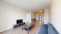 This thoughtfully designed 2-bedroom, 1-bathroom residence is arranged across a single floor, offering a practical and cohesive living experience. The living room is bright and open, featuring light hardwood-style flooring, neutral walls, and large glass sliding doors that invite abundant natural light and provide direct access to an outdoor area with exterior views. The clean, minimalist aesthetic of the space allows for versatile furnishing arrangements.

The kitchen is efficiently laid out with warm-toned cabinetry extending to the ceiling, white tile backsplash, and a full suite of stainless steel appliances including a refrigerator, gas range, microwave, and dishwasher. A compact dining area adjacent to the kitchen provides a convenient space for everyday meals.

The primary bedroom is a well-proportioned room with soft carpeting, a window offering outdoor views, and access to a dedicated closet featuring louvered doors and built-in shelving. The second bedroom is similarly finished with plush carpet and a bright window. The shared bathroom is clean and modern, equipped with a single vanity, large mirror, and a glass-enclosed walk-in shower with tile surround. Overall, the space presents a cohesive, contemporary design with a light, neutral palette throughout.