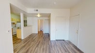 Located at 2600 Americare Ct NW in Albuquerque, New Mexico, this single-floor residential unit offers a functional and comfortable layout designed for everyday living. The living room serves as the heart of the home, featuring warm hardwood-style flooring, a sliding glass door that fills the space with natural light and provides patio access, and ample room for relaxed seating arrangements. The space flows directly into a dedicated dining area, illuminated by a pendant light overhead and comfortably sized for a four-person table. Adjacent to the dining area, the kitchen is outfitted with light wood cabinetry, a full suite of white appliances including a refrigerator and electric range, and generous counter space for meal preparation. The bedrooms are carpeted for comfort, each offering closet storage and windows for natural light. One bedroom is well-suited as a secondary or children's room, while the primary bedroom provides a quiet retreat. Two full bathrooms serve the unit, each featuring a shower-tub combination, vanity with sink, and adequate storage. Throughout the unit, textured ceilings and neutral wall tones create a clean, bright atmosphere that is both practical and welcoming.
