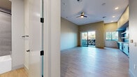Located at 6901 E Main St in Scottsdale, Arizona, this single-floor unit offers a well-designed, efficiently organized layout. The open-concept kitchen and living area serves as the heart of the space, featuring light wood-style flooring that flows throughout. The kitchen is outfitted with modern stainless steel appliances — including a gas range, microwave, dishwasher, and a side-by-side refrigerator — complemented by light wood cabinetry, white lower cabinets, a blue subway tile backsplash, and white countertops. The living area is bright and airy, with a ceiling fan overhead and a sliding glass door that opens to a private balcony, allowing natural light to fill the space and providing views of the surrounding Scottsdale streetscape. An additional window further enhances the sense of openness. The two bathrooms are finished with large-format gray tile surrounding a soaking tub and shower combination, matte black fixtures, and wood-look flooring, offering a clean, contemporary aesthetic. A dedicated closet provides practical storage. Neutral warm-toned walls and consistent flooring tie the space together, creating a cohesive and modern living environment ideally situated in the heart of Old Town Scottsdale.