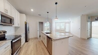 This well-appointed single-floor residence showcases a thoughtfully designed open-concept layout that seamlessly connects the kitchen, dining, and living areas. The kitchen serves as the centerpiece of the home, featuring a large granite-topped island with an undermount sink, white shaker cabinetry, a sleek tile backsplash, and a full suite of stainless steel appliances including a refrigerator with ice maker, electric range, microwave, and dishwasher. Stylish pendant lights hang above the island, adding warmth to the bright, airy space. Light wood-look flooring extends throughout the main living areas, enhancing the clean, contemporary aesthetic.

The living area is generously proportioned, bathed in natural light from multiple windows fitted with horizontal blinds. The bedrooms are carpeted for comfort, each offering ceiling fans and ample natural light. A walk-in closet provides convenient storage in one of the bedrooms.

The bathrooms are finished with granite countertops and white cabinetry. The primary bathroom features a double-sink vanity with a large framed mirror and a separate tub-shower combination. A secondary bathroom mirrors the same refined finishes. A dedicated laundry closet with shelving rounds out this clean, move-in-ready home.