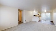 This single-floor residence offers a straightforward, efficiently organized layout comprising three bedrooms, two full bathrooms, a living room, a kitchen, a hallway, and a closet. The overall footprint provides a compact yet functional living environment designed to maximize usability across each room.

The living room features neutral-toned carpet, white walls, and connects openly to the kitchen via a half-wall peninsula, creating a cohesive common area. A large window near the entry door allows natural light to filter in, brightening the space. The kitchen is laid out in a galley configuration with wood-look flooring, warm-toned laminate countertops, white cabinetry, and black appliances including a refrigerator, electric range, and dishwasher.

The three bedrooms are carpeted and finished with neutral walls. Each room features a window providing natural light and outdoor views. The primary bedroom includes access to a dedicated walk-in closet equipped with wire shelving systems for organized storage. A wall heater unit is present in at least one bedroom.

Both bathrooms share a consistent design, each featuring a tub-shower combination with chrome fixtures, wood-look flooring, a toilet, and a vanity with a warm-toned countertop. The overall aesthetic throughout the unit is clean and understated.
