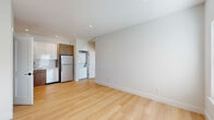 Located at 181 Freeman Ave in Islip, NY, this single-floor unit showcases a clean, modern design throughout. Light hardwood flooring runs continuously across the living areas and bedrooms, creating a cohesive and bright aesthetic complemented by neutral white walls and recessed lighting.

The kitchen is well-appointed with a two-tone cabinet scheme, pairing white upper cabinetry with warm wood-toned lower cabinets. A full suite of stainless steel appliances includes a gas range, microwave, dishwasher, and refrigerator, alongside a subway tile backsplash and ample storage. An adjacent closet provides additional pantry or storage space.

The living area offers an open, airy feel with natural light filtering through blinded windows. Multiple rooms serve as flexible bedroom or living spaces, each featuring light hardwood floors, neutral walls, and windows with blinds. One room includes direct access to a dedicated in-unit laundry area housing a stacked washer and dryer.

The bathroom is finished with large-format marble-style tile on both the floors and shower walls, complemented by a glass-enclosed shower with a sleek chrome sliding door and built-in shelving, lending an upscale, polished look to the space.