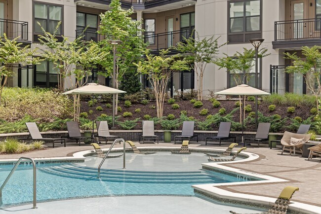 Piscina estilo resort con zona para tomar el sol, cabañas y terraza. - Bexley Chamblee