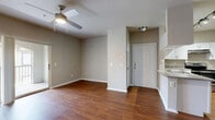 Located in Temple Terrace, Florida, this single-story, 3-bedroom, 2-bathroom home offers a functional and well-organized layout. The open-concept living and kitchen area serves as the heart of the home, featuring rich hardwood-style flooring that flows throughout the main living spaces. The kitchen is equipped with stainless steel appliances — including a refrigerator and electric range — white cabinetry, a double-basin sink, and a peninsula with countertop workspace that opens toward the living area. The living room benefits from natural light through a large arched sliding glass door dressed with vertical blinds, complemented by a ceiling fan overhead.

Each of the three bedrooms is carpeted and features ceiling fans, neutral wall tones, and access to closet space. The primary bedroom is generously sized and includes a walk-in closet outfitted with wire shelving across multiple levels. The two bathrooms each feature wood-style flooring, a tub-shower combination with tile surround, a single-sink vanity with a stone-style countertop, and white cabinetry with brushed nickel hardware. A dedicated utility room and a connecting hallway complete the interior layout, offering practical storage and circulation throughout the home.