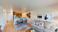 Located at 1465 W Deer Crest St in Meridian, Idaho, this two-story home offers a well-designed layout with a clean, contemporary aesthetic throughout. The main level showcases an open-concept living, dining, and kitchen area bathed in warm recessed lighting and finished with light hardwood flooring. The kitchen is thoughtfully appointed with rich warm-toned cabinetry, granite countertops, stainless steel appliances, and a peninsula with bar seating — ideal for casual dining or entertaining. The adjoining dining area flows naturally into the living room, which features a sliding glass door opening to a private, fenced backyard with a landscaped outdoor area, bringing in generous natural light and outdoor views. The bedrooms offer plush carpeting and a calm, neutral palette, providing a restful retreat. One flexible room serves well as a home office or additional bedroom, with a bright window and comfortable proportions. The bathrooms are finished consistently with granite-topped vanities, warm wood cabinetry, and tub-shower combinations. Crisp white walls, panel-style interior doors, and cohesive finishes tie the home together across both floors, creating a functional and inviting living environment throughout.