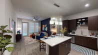 This single-floor residence is thoughtfully designed with a contemporary aesthetic, blending open-concept living with distinct, well-defined spaces. The kitchen serves as a central hub, outfitted with dark espresso cabinetry, quartz countertops, and a full suite of stainless steel appliances including a side-by-side refrigerator, electric range, built-in microwave, and dishwasher. A large island with pendant lighting above provides both additional prep space and casual seating, creating a natural transition into the living area.

The open living room is anchored by a bold navy accent wall adorned with vibrant artwork, contrasting with light wood-style flooring and a ceiling fan that runs throughout the main living space. Large windows allow generous natural light to fill the area, enhancing its airy feel.

The primary bedroom features its own deep blue accent wall, ceiling fan, large windows, and wood-style flooring, conveying a calm, restful atmosphere. Its en-suite bathroom includes a granite-topped vanity with dark cabinetry, a walk-in shower, and a backlit mirror. A second bedroom showcases a vivid teal accent wall and ample natural light. The second bathroom offers a full soaking tub and shower combination with a similarly styled vanity, completing the cohesive, modern design throughout.