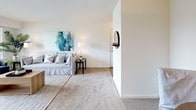 This single-floor residence offers a thoughtfully organized layout that balances functionality with comfort. The living room serves as a bright, welcoming focal point, featuring neutral carpet flooring, large windows that invite natural light, and ample space for seating arrangements. A dedicated dining area adjoins the living space, accommodating a round wooden table and complemented by soft wall art in cool, coastal tones.

The galley-style kitchen is efficiently designed with light wood cabinetry, granite-style countertops, a full suite of white appliances including a dishwasher and refrigerator, and durable hardwood-style flooring. Generous upper and lower cabinet storage ensures practical everyday use.

The primary bedroom is notably spacious, featuring plush carpet, multiple windows with outdoor views of greenery, and direct access to a private en-suite bathroom. An adjacent closet provides dedicated storage. A second bedroom mirrors this comfortable scale, also benefiting from natural light through dual windows.

The bathrooms are clean and functional, with tiled flooring and a tub-shower combination. Throughout the residence, the consistent use of neutral tones, soft carpeting, and natural light creates a calm, cohesive ambiance well-suited for everyday living.