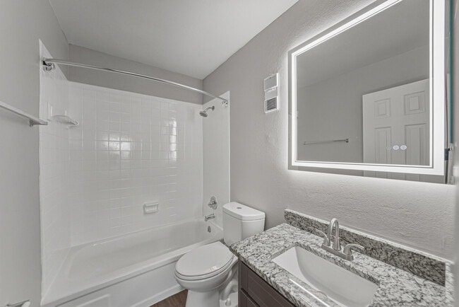 Updated two-bedroom apartment bathroom with granite vanity and modern lighting - Magnolia Apartments