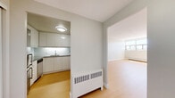 Located on Wellington Street West in Ottawa's vibrant Hintonburg neighbourhood, this 2-bedroom, 1-bathroom unit features a thoughtfully designed single-floor layout. Light hardwood flooring runs throughout the living areas and bedrooms, creating a warm, cohesive aesthetic against the neutral grey-toned walls and bright white trim.

The kitchen is efficiently laid out with sleek, high-gloss white cabinetry extending to the ceiling, a stainless steel electric range with an overhead exhaust, a single-basin undermount sink, and a light tile backsplash. Under-cabinet lighting adds a clean, contemporary finish.

The spacious primary bedroom is generously proportioned and features a large window that allows natural light and outdoor views to fill the room, complemented by a baseboard heating unit. The second bedroom is bright and functional, also finished with the same warm hardwood flooring.

The bathroom is finished in white throughout, featuring full-height subway tile surrounding the soaker tub and shower, a modern vanity with under-sink storage, a large mirror, and clean chrome fixtures.

A connecting hallway anchors the layout, providing access to all rooms, including a glimpse of the kitchen from the entry. Baseboard heating units are present throughout, ensuring year-round comfort in this clean, move-in-ready unit.