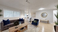 Located at 3600 Park Colony Dr in Norcross, Georgia, this single-floor home offers a thoughtfully designed layout with a cohesive, modern aesthetic throughout. Light wood flooring runs continuously across the main living areas, creating a bright and airy atmosphere that ties each space together seamlessly.

The living area is generously proportioned, featuring neutral walls, a textured ceiling, and multiple windows dressed with white horizontal blinds that allow for ample natural light. The space flows openly into a dedicated dining nook, which is enclosed by large windows on two sides, offering a bright and inviting setting for everyday meals.

Adjacent to the dining area, the galley-style kitchen is a functional highlight, outfitted with gray cabinetry, white subway tile backsplash, marble-look countertops, and stainless steel appliances. The layout maximizes counter and storage space along both walls, making it efficient and practical.

A wide hallway connects the private areas of the home, with light wood flooring continuing underfoot and framed artwork adding character to the corridor. The bathroom features a full soaking tub with a tiled surround in a neutral stone-look finish, complemented by chrome fixtures for a clean, polished look.

Throughout the home, the design balances modern updates with comfortable, livable spaces, making it a well-rounded and move-in-ready residence in the Norcross community.