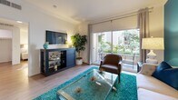 Located at 1026 S Broadway in Los Angeles, this well-appointed one-bedroom, one-bathroom residence offers a thoughtfully designed single-level layout. The open-concept living, dining, and kitchen area serves as the heart of the home, anchored by warm hardwood-style flooring and crown molding throughout. A bold teal accent wall adds a striking visual focal point to the combined living and dining space, which features a tufted sofa, glass coffee table, and a dining area with floating wall shelves. Sliding glass doors open to a private balcony overlooking lush, verdant greenery, flooding the interior with natural light. The galley-style kitchen is outfitted with rich wood cabinetry, dark granite countertops, tile flooring, and stainless steel appliances including a gas range and dishwasher. The spacious primary bedroom offers generous proportions, large windows with garden views, and access to three closets. The bathroom features a warm wood vanity with a granite countertop, a combined tub and shower, tile flooring, and soft blue walls that evoke a calm, spa-like ambiance. An in-unit laundry area completes this efficiently designed urban residence.