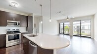 Located on South Howard Avenue in Tampa's desirable 33629 corridor, this single-floor residence offers a thoughtfully designed open-concept layout with contemporary finishes throughout. The kitchen serves as the centerpiece of the living area, featuring dark espresso cabinetry, stainless steel appliances including a refrigerator, range, microwave, and dishwasher, and a curved white quartz island with an integrated sink. Dual pendant lights hang above the island, adding a refined touch, while rich dark hardwood flooring extends throughout the main living and kitchen areas. The living space opens toward floor-to-ceiling glass doors that lead to a balcony, allowing natural light to fill the room, complemented by a ceiling fan overhead.

The bedrooms are carpeted for comfort, each featuring ceiling fans and windows that bring in natural light and outdoor views. One bedroom includes access to a generously sized walk-in closet outfitted with multi-tiered wire shelving and hanging rods. Two bathrooms serve the unit: one with a soaking tub and tiled surround, and another with a glass-enclosed walk-in shower. Both feature light tile flooring, white quartz vanities, and wood-toned cabinetry, maintaining a clean and cohesive modern aesthetic throughout.