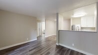 Located at 896 Davis St in San Leandro, CA, this single-story unit offers a thoughtfully designed layout with contemporary finishes throughout. The open living and dining area is anchored by durable wood-style flooring in a warm gray tone, neutral beige walls, and clean white baseboards, creating a bright and cohesive aesthetic. A sliding glass door leads to a private outdoor balcony, allowing natural light to fill the space and providing a seamless indoor-outdoor connection.

The kitchen is well-appointed with white shaker upper cabinets, gray lower cabinets, granite-style countertops, and a full suite of stainless steel appliances including a gas range, refrigerator, and dishwasher. A pass-through design connects the kitchen to the main living area, enhancing the open feel of the floor plan.

The bedroom features plush carpeting and a wide sliding-door closet offering ample storage. The bathroom is finished with wood-look flooring, a granite-topped vanity, and grab bars for added convenience. A built-in storage closet is also visible in the hallway area. The overall ambiance is clean, modern, and move-in ready.