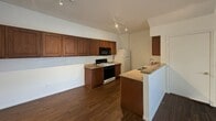 This 960-square-foot, single-story residence at 5880 Boulder Falls St in Henderson, Nevada offers a practical and well-organized layout across three bedrooms and two bathrooms. The open living room greets you with dark hardwood-style flooring, a ceiling fan with light fixture, and a sliding glass door fitted with vertical blinds that fills the space with natural light and provides outdoor access. The kitchen is efficiently designed with rich walnut-toned cabinetry, granite-style countertops, a double stainless steel sink, a gas range with microwave above, a refrigerator, and track lighting overhead. A peninsula counter separates the kitchen from the living area, enhancing the open feel. The three bedrooms feature plush carpet flooring and vertical-blind windows that allow natural light. The primary bedroom measures 170 square feet and includes a ceiling fan and a mirrored sliding-door closet. Both bathrooms are appointed with granite-style vanity countertops, tub-shower combinations with white tile surrounds, and dark hardwood-style flooring. A hallway connects the private areas of the home. The consistent use of dark flooring throughout the common areas and clean, neutral wall tones gives the home a cohesive and move-in-ready appeal.