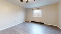 This 260 square foot apartment in Albion, NY, offers a thoughtfully designed living space that maximizes efficiency and comfort. The single-floor layout comprises a modern kitchen, updated bathroom, and open living area. The kitchen features a sleek design with white cabinetry, contrasting with a black refrigerator and stainless steel range. Light-colored wood-look flooring runs throughout, creating a sense of continuity and spaciousness. The bathroom boasts a clean, white aesthetic with a combination tub-shower unit and a single vanity. The living area is illuminated by natural light from a window, complemented by ceiling-mounted light fixtures. A ceiling fan in the main living space provides additional comfort. Despite its compact size, the apartment offers ample storage solutions and a cohesive design that makes efficient use of the available square footage. The neutral color palette and contemporary finishes contribute to a fresh, inviting atmosphere in this well-appointed urban dwelling.