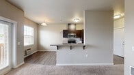 This single-story, one-bedroom, one-bathroom unit offers a thoughtfully organized layout across a comfortable footprint. The open-concept living and kitchen area serves as the heart of the unit, where wood-style flooring flows throughout. The kitchen is outfitted with dark espresso cabinetry, granite-style countertops, and a full suite of stainless steel appliances including a refrigerator, electric range, microwave, and dishwasher. A peninsula with an extended granite-style breakfast bar separates the kitchen from the living area, providing both additional counter space and casual seating. A pendant light fixture and a window allowing natural light add character to the living space.

The bedroom is a well-proportioned, carpeted room featuring a window with an exterior view and a sliding-door closet with built-in shelving and a hanging rod. The bathroom is tiled and includes a dark-cabineted vanity with a granite-style countertop and an integrated sink. Notably, in-unit washer and dryer connections—with full-size appliances included—are situated adjacent to the bathroom, adding significant convenience. Neutral wall tones and consistent finishes throughout contribute to a cohesive, functional living environment.