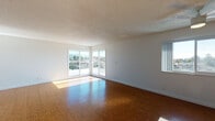 Located at 360 Estabrook St in San Leandro, California, this single-floor residence offers a clean, modern aesthetic throughout. Warm hardwood-style flooring runs continuously across the living spaces, complementing the bright white walls and creating a cohesive, inviting atmosphere.

The expansive living area is a standout feature, bathed in abundant natural light streaming through large sliding glass doors and wide windows that frame views of the surrounding neighborhood. A ceiling fan adds to the comfort of this generously sized room. A textured ceiling adds subtle architectural character to the space.

The kitchen is thoughtfully designed with white cabinetry, dark countertops, stainless steel appliances including a range and refrigerator, and a dedicated range hood. A peninsula separates the kitchen from the adjacent dining area, which features a stylish pendant light fixture. A door with a windowed panel provides convenient exterior access directly from the kitchen.

The bedrooms are well-proportioned, each featuring ceiling fans and hardwood-style flooring. One bedroom includes a full-length mirror closet door, maximizing both storage and the sense of space.

Two bathrooms serve the unit: one features a tub-shower combination with white tile surround and a window for natural light, while the second offers a glass-enclosed standing shower with clean, contemporary finishes. Both bathrooms maintain a bright, crisp look with white fixtures and hardwood-style flooring.