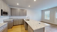Located at 100 Watlington Dr in Calhoun, Georgia, this two-story home offers a well-planned layout across two floors. The main level features an open-concept kitchen and living area bathed in natural light from multiple windows fitted with blinds. The kitchen is a standout, showcasing granite countertops, a large central island with a built-in sink, taupe shaker-style cabinetry, stainless steel appliances, and recessed lighting — all complemented by warm light wood flooring that flows throughout the home. A ceiling fan adds comfort to the living area, which opens to an exterior door with outdoor views. The main level also includes an attached garage with an automatic opener and a convenient pantry. A staircase with wood-tread steps and a clean white railing leads to the upper floor, where all three bedrooms are located. Each bedroom features light wood flooring, neutral walls, and access to closets outfitted with wire shelving systems. The primary bedroom offers a generous footprint. Three full bathrooms and a dedicated laundry room round out the home's functional spaces. Hallways connect the rooms efficiently, and multiple closets throughout provide ample storage. The home presents a clean, modern aesthetic with a neutral palette ideal for any décor.