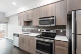 This thoughtfully designed single-floor residence showcases a clean, modern aesthetic with consistent attention to detail throughout. The galley-style kitchen is a standout feature, equipped with stainless steel appliances including a range, microwave, dishwasher, and refrigerator. Rich wood-tone cabinetry paired with a crisp white quartz countertop and a sleek tile backsplash give the kitchen a polished, contemporary feel. The kitchen flows seamlessly into the open living area, which benefits from generous natural light and dark hardwood-style flooring that extends throughout the main living spaces.

The bedroom is bright and airy, highlighted by large floor-to-ceiling windows that frame views of the surrounding urban streetscape. A sliding frosted-glass closet door adds a modern touch while maximizing the sense of openness in the room.

The bathroom is finished with a floating wood-tone vanity, a white undermount sink, a large mirror, and dark hardwood-style flooring that contrasts cleanly with the neutral wall tones. Brushed nickel hardware and towel bars complete the refined look.

Throughout the unit, recessed lighting, smooth ceilings, and a neutral color palette create a cohesive and inviting atmosphere well-suited for contemporary urban living.